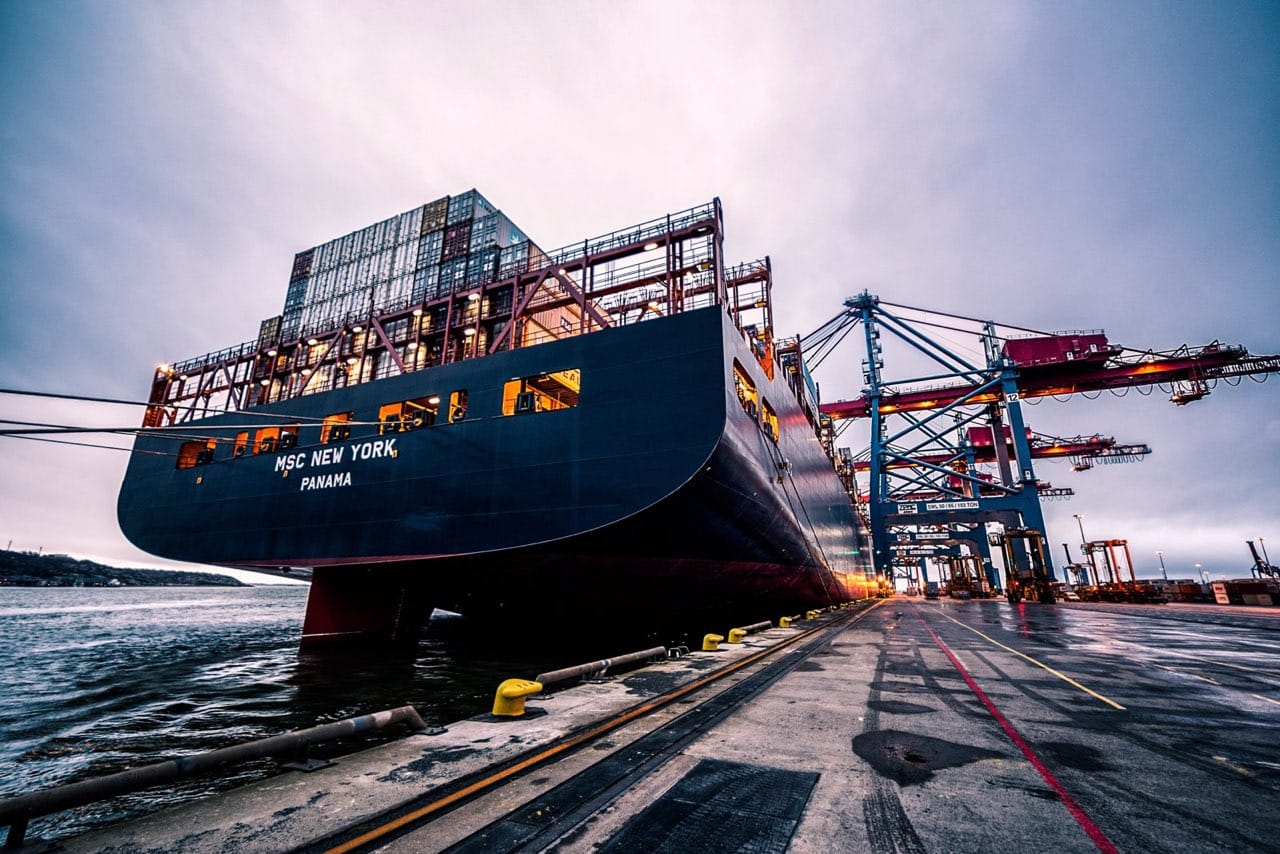 Container ship docked under port cranes for international freight shipping
